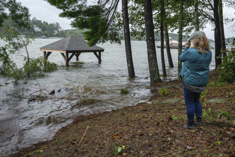 Julie Cioffoletti looks at her flooded gazebo and steps to her dock in her backyard after Hurricane Helene passed the area on Lake James, Friday, Sept. 27, 2024 in Morganton, N.C. (AP Photo/Kathy Kmonicek)