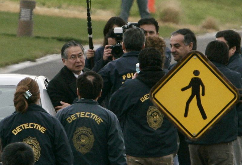 FILE - Chilean police officers surround former Peru's President Alberto Fujimori, left, as he leaves his house in Santiago to be extradited to Peru to face human rights and corruption charges, early Sept. 22, 2007. (AP Photo/Claudio Santana, File)