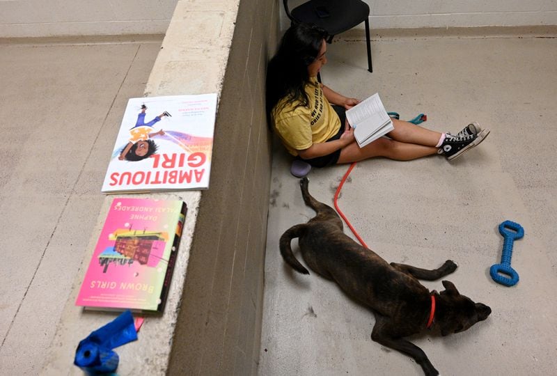 Leslie Moffett reads a book to shelter dog King at Cobb County Animal Services, Saturday, May 20, 2023, in Marietta. Moffett found that reading to the dogs can help rehabilitate them, especially in a chaotic shelter environment. (Hyosub Shin / Hyosub.Shin@ajc.com)