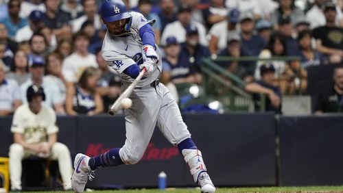 Los Angeles Dodgers' Mookie Betts, right, hits an RBI single during the seventh inning of a baseball game against the Milwaukee Brewers, Monday, Aug. 12, 2024, in Milwaukee. (AP Photo/Aaron Gash)