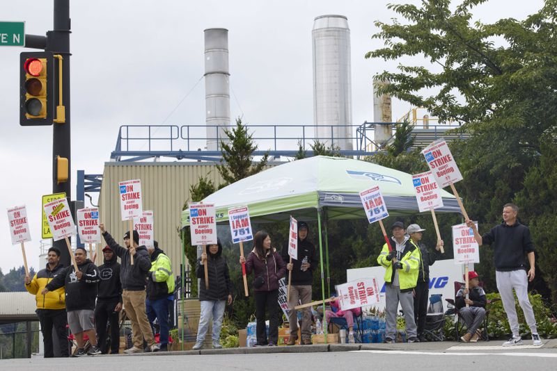 Boeing Machinists Union members react to passing vehicles while on the picket line at the company's factory in Renton, Wash., on Saturday, Sept. 14, 2024. (AP Photo/John Froschauer)