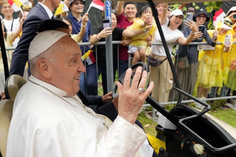 Pope Francis waves to greet the volunteers on his arrival in Singapore, Wednesday, Sept. 11, 2024. (AP Photo/Vincent Thian)