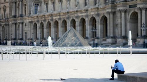 A lone man sit in the shadow in the courtyard of the Louvre museum, which is outside the security perimeter set up for the Olympic Games, Friday, July 19, 2024, in Paris, France. (AP Photo/David Goldman)