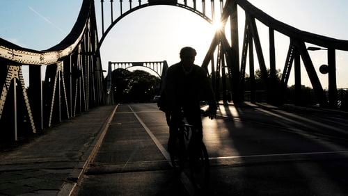 FILE - A cyclist passes over the Glienicke Bridge between Potsdam and Berlin, Germany, on May 6, 2009. They sometimes see those who are part of the swap as they pass each other on an airport tarmac or, as in the Cold War, the Glienicke Bridge connecting West Berlin to Potsdam. In decades of prisoner exchanges, those released have included spies, journalists, drug and arms dealers, and even a well-known athlete. (AP Photo/Sven Kaestner, File)