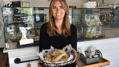 Belén de la Cruz holds a basket of empanadas in the ordering and dining area of her Johns Creek shop.