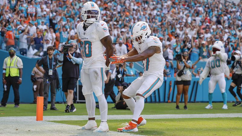 Miami Dolphins wide receiver Tyreek Hill (10) holds his hands behind his back as if he is handcuffed as Miami Dolphins wide receiver Jaylen Waddle (17) unlocks them after Hill scores against the Jacksonville Jaguars in the second half during an NFL football game at Hard Rock Stadium in Miami Gardens, Florida, on Sunday, Sept. 8, 2024. (Al Diaz/Miami Herald via AP)