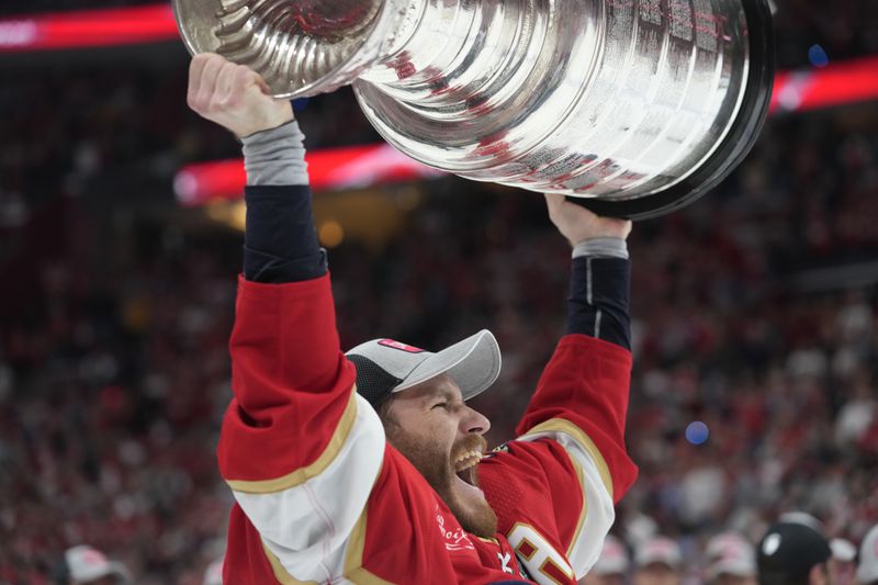 FILE - Florida Panthers left wing Matthew Tkachuk raises the Stanley Cup trophy after defeating the Edmonton Oilers, Monday, June 24, 2024, in Sunrise, Fla. (AP Photo/Wilfredo Lee, File)