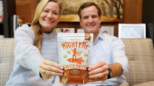 Founders of the nut butter puffs Mission MightyMe, Catherine and J.J. Jaxon, pose in their house holding one of their products on as they celebrate a recent deal with Target. Wednesday, August 28, 2024.
(Miguel Martinez / AJC)