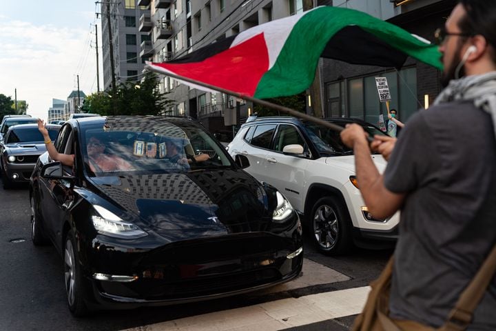 A protester waves a Palestinian flag in front of a car displaying Israeli and American flags at the intersection of 10th Street NW and Spring Street NW in Atlanta on Thursday, June 27, 2024. Nearby, President Joe Biden and former President Donald Trump participated in a debate hosted by CNN. (Seeger Gray / AJC)