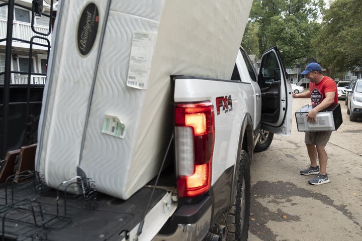 Dexter Leach loads up his daughter’s microwave while helping her move out of her flooded apartment at the Peachtree Park Apartments in Atlanta on Saturday, Sept. 28, 2024.   Ben Gray for the Atlanta Journal-Constitution