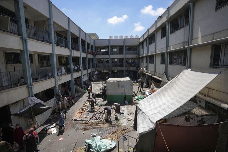 Palestinians tear down a tent as they evacuate a school that had been their shelter, in eastern Deir al-Balah, Gaza Strip, Friday, Aug. 16, 2024, after the Israeli military dropped leaflets asking civilians to evacuate from the area and northern Khan Younis, saying forces plan to respond to rocket fire that targeted Israel. (AP Photo/Abdel Kareem Hana)