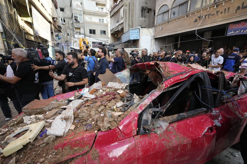 Journalists gather at the scene of a building that was hit by an Israeli airstrike in Beirut's southern suburbs, Tuesday, Sept. 24, 2024. (AP Photo/Hassan Ammar)