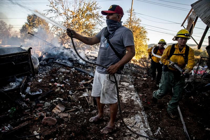 Gaudencio Ortiz douses water on a destroyed structure adjacent to his friend's home during the Boyles fire in Clearlake, Calif., Sunday, Sept. 8, 2024. (Stephen Lam/San Francisco Chronicle via AP)