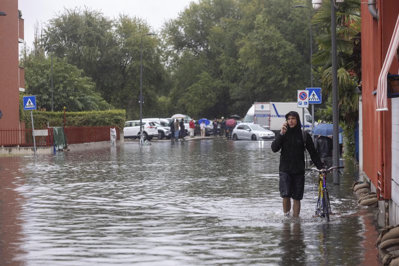 Residents walk through flooded streets in Milan, northern Italy, Thursday, Sept. 5, 2024. Lombardy and Veneto have been hit by widespread flooding, causing damage and disruption in the city of Milan, where the local Seveso and Lambro rivers overflowed. (Stefano Porta/LaPresse via AP)