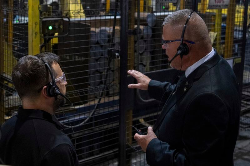 In this photo provided by the U.S. Army, Ukrainian President Volodymyr Zelenskyy, left, listens to Rich Hansen, the commander's representative for the Scranton Army Ammunition Plant, while observing metal being cut down to billets as part of the projectile cartridge case production process at the ammunition plant in Scranton, Pa., Sunday, Sept. 22, 2024. (Sgt. 1st Class Curt Loter/U.S. Army via AP)