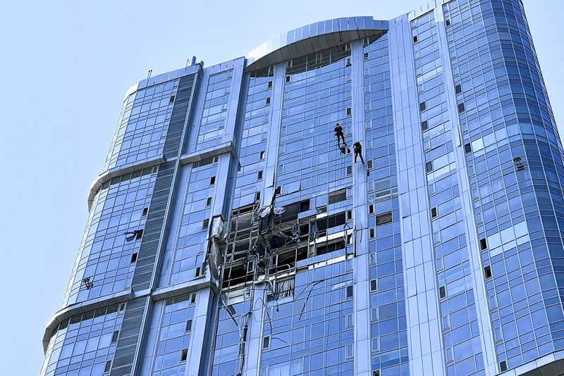 This photo released by the governor of the Saratov region, Roman Busargin, in his official Telegram channel on Monday, Aug. 26, 2024, shows municipal employees working at the side of a damaged building after a drone attack on the city of Saratov, Russia. (Saratov region governor Roman Busargin official Telegram channel via AP)