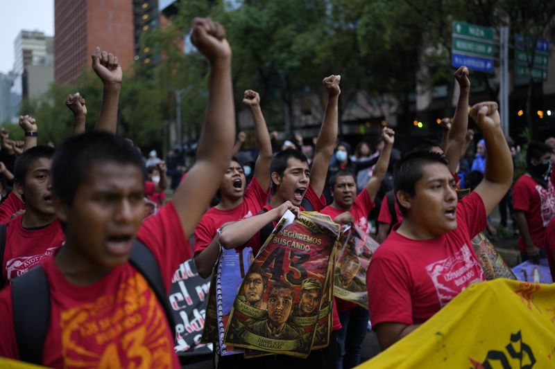 Youths chant and raise their fists in unison as they take part in a demonstration marking the 10-year anniversary of the disappearance of 43 students from an Ayotzinapa rural teacher's college, in Mexico City, Thursday, Sept. 26, 2024. (AP Photo/Eduardo Verdugo)