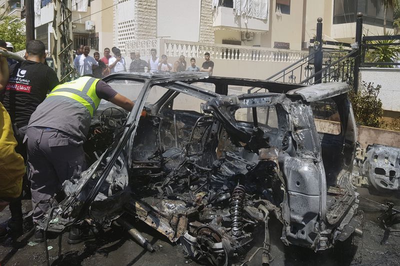 A Civil Defense worker inspects the remains of a burned car that was hit by an Israeli strike in the southern port city of Sidon, Monday, Aug. 26, 2024. After a short-lived calm following a heavy exchange of strikes between Israel and the Lebanese militant group Hezbollah, fighting resumed Monday. (AP Photo/Mohammed Zaatari)