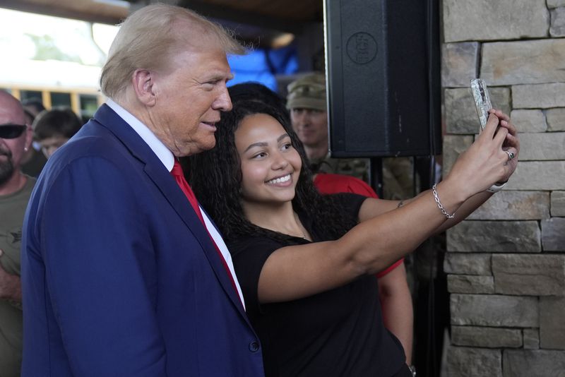 Republican presidential nominee former President Donald Trump greets people at a temporary relief shelter as he visits areas impacted by Hurricane Helene, Friday, Oct. 4, 2024, in Evans, Ga. (AP Photo/Evan Vucci)