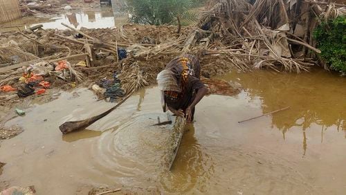 A woman sorts through floodwaters near her damaged home near the city of Abu Hamdan in Northern Sudan on Aug. 7, 2024. (AP Photo/ Samira Hassan)