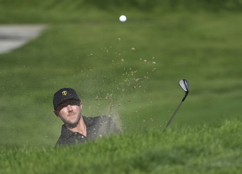 International team member Mackenzie Hughes, of Canada, hits out of a bunker on the fifth hole during a fifth-round singles match at the Presidents Cup golf tournament at Royal Montreal Golf Club, Sunday, Sept. 29, 2024, in Montreal. (Christinne Muschi/The Canadian Press via AP)