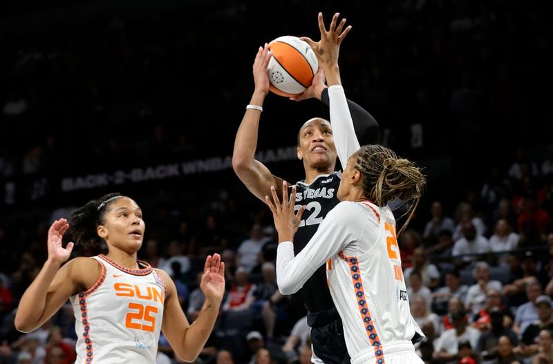 Las Vegas Aces center A'ja Wilson (22) shoots between Connecticut Sun forwards Alyssa Thomas (25) and DeWanna Bonner (24) during the first half of an WNBA basketball game Sunday, Sept. 15, 2024, in Las Vegas. (Steve Marcus/Las Vegas Sun via AP)