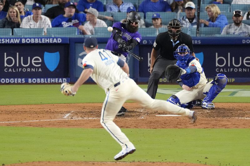 Colorado Rockies' Charlie Blackmon, second from left, hits a two-run home run as Los Angeles Dodgers relief pitcher Daniel Hudson, left, watches along with Los Angeles Dodgers' Hunter Feduccia, right, and home plate umpire Jeremie Rehak during the ninth inning of a baseball game, Saturday, Sept. 21, 2024, in Los Angeles. (AP Photo/Mark J. Terrill)