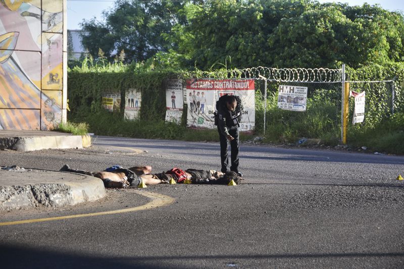 A police officer photographs a crime scene of bodies lying on the ground in Culiacan, Sinaloa state, Mexico, Wednesday, Sept. 18, 2024. (AP Photo)