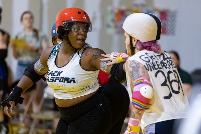 Darlane Besand (left), aka Sprint Julep, scrimmages at the Atlanta Roller Derby practice facility in Mableton on Wednesday, May 22, 2024. (Arvin Temkar / AJC)
