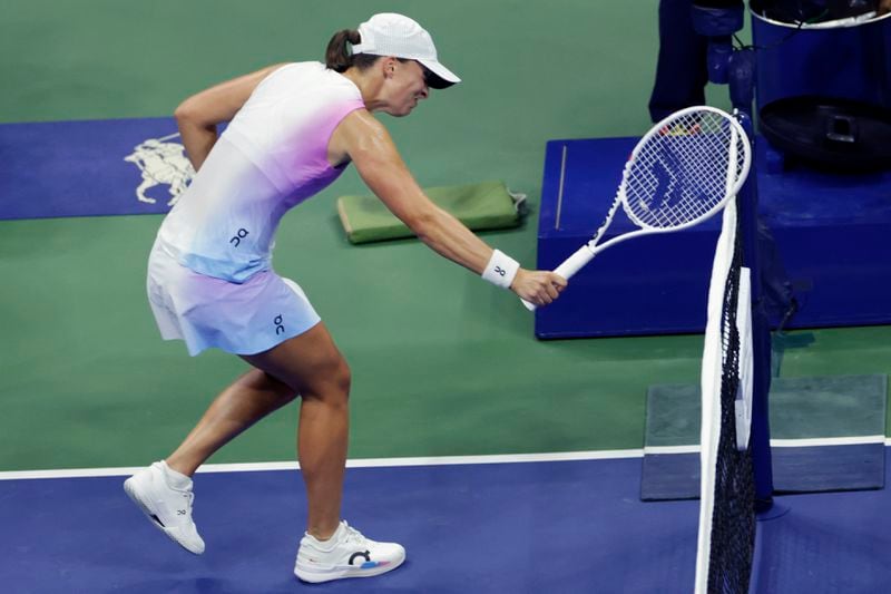 Iga Świątek, of Poland hits the net with her racquet after losing a point to Jessica Pegula, of the United States during the quarterfinals of the U.S. Open tennis championships, Wednesday, Sept. 4, 2024, in New York. (AP Photo/Adam Hunger)