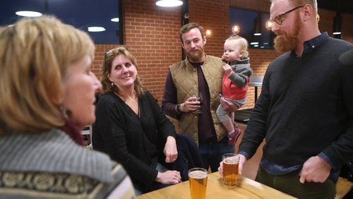 Furloughed workers Daria Labinsky (from left), Maureen Hill, Chip Daymude with his daughter Penny, 18-months, and Nathan Jordan discuss the shutdown at Sweetwater Brewing Company during an event offering free food and beer to furloughed federal workers on Thursday, Jan. 10, 2019, in Atlanta.