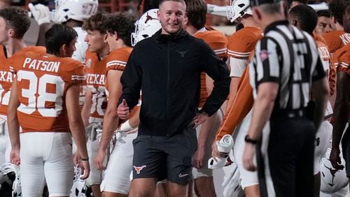 Texas quarterback Quinn Ewers, center, stands on the sidelines in street cloths after he was injured during the second half of an NCAA college football game against UTSA in Austin, Texas, Saturday, Sept. 14, 2024. (AP Photo/Eric Gay)