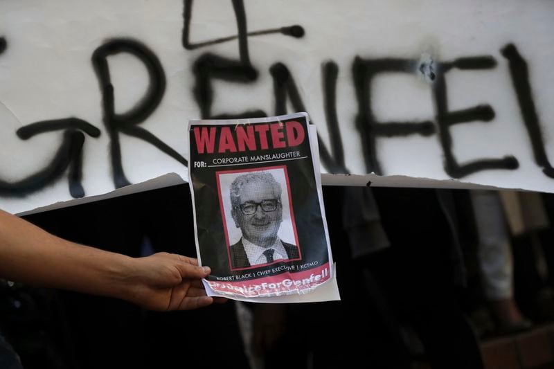 FILE - People hold up a sign with the image of Chief Executive of Kensington and Chelsea Tenant Management Organisation Robert Black, during a protest outside Kensington Town Hall following the Grenfell Tower fire in London, Friday June 16, 2017. (AP Photo/Tim Ireland, File)