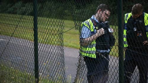 Police officers stand next to a hole in the fence at Cologne/Bonn Airport, Germany, Wednesday July 24, 2024. Climate activists have caused an interruption to air traffic at Cologne/Bonn Airport. (dpa via AP)