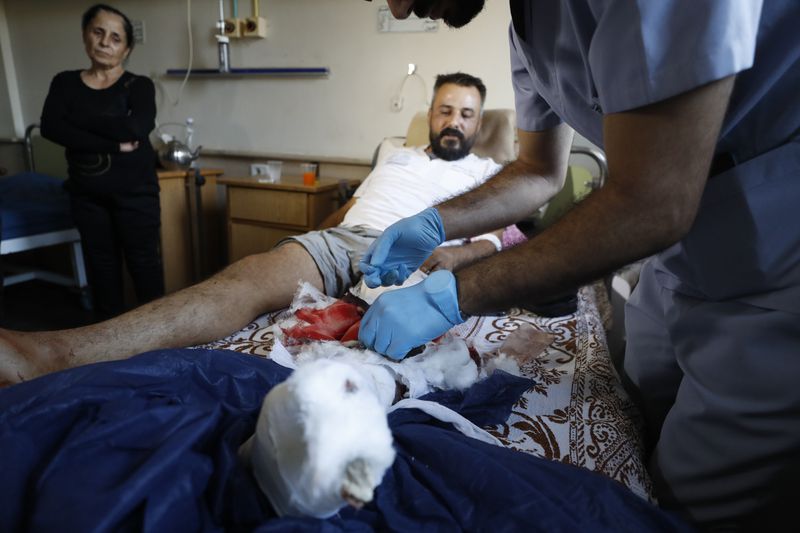 A Syrian nurse treats an man, who was injured, in the town of Masyaf, Syria, Monday, Sept. 9, 2024. Syrian state news agency SANA says that Israeli strikes hit several areas in central Syria Sunday night, damaging a highway in Hama province and sparking fires. (AP Photo/Omar Sanadiki)