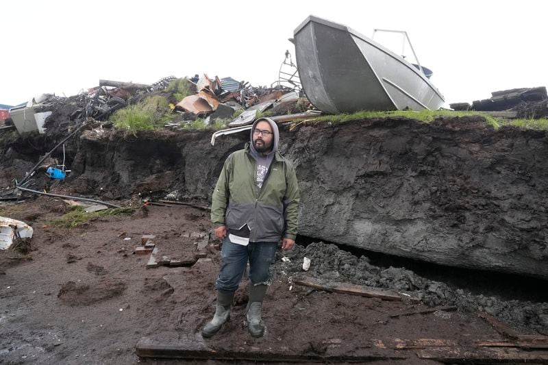 Calvin Tom, the tribal administrator, stands along the eroded coastline in Newtok, Alaska on Friday, Aug. 16, 2024. (AP Photo/Rick Bowmer)