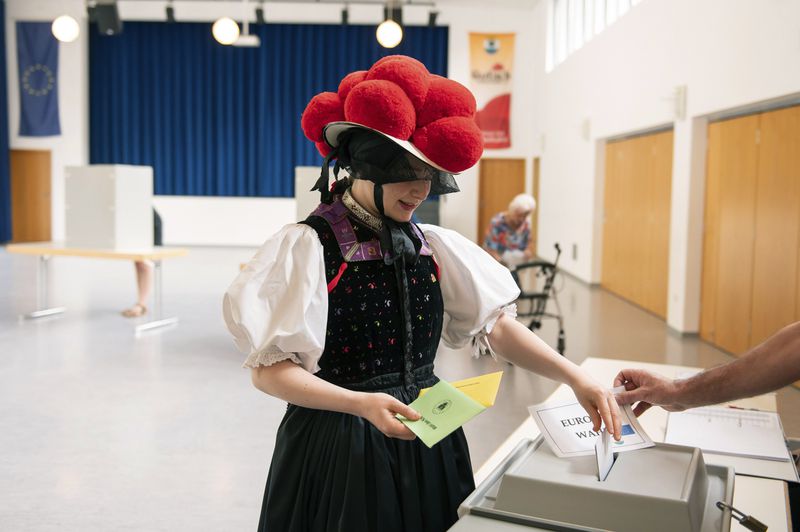 Katharina Moser, dressed in traditional Black Forest attire. with red Bollenhut hat, casts her ballot for the European Parliament elections at the polling stationm in Gutach im Breisgau, Germany, Sunday, June 9, 2024. (Silas Stein/dpa via AP)