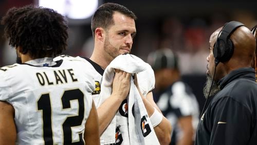 New Orleans Saints quarterback Derek Carr, center, speaks on the sidelines during the second half of an NFL football game against the Atlanta Falcons, Sunday, Sept. 29, 2024, in Atlanta. (AP Photo/Butch Dill)