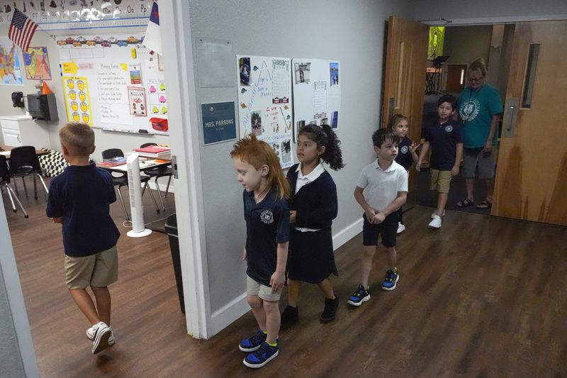 First grade students return to the classroom after a chapel service at the Winter Garden Christian Academy, Thursday, Aug. 29, 2024, in Winter Garden, Fla. (AP Photo/John Raoux)