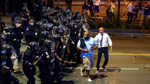 Charlotte-Mecklenburg police officers begin to push protesters from the intersection near the Epicentre in Charlotte, N.C. Wednesday, Sept. 21, 2016. Authorities in Charlotte tried to quell public anger Wednesday after a police officer shot a black man, but a dusk prayer vigil turned into a second night of violence, with police firing tear gas at angry protesters and a man being critically wounded by gunfire. North Carolina's governor declared a state of emergency in the city. (Jeff Siner/The Charlotte Observer via AP)