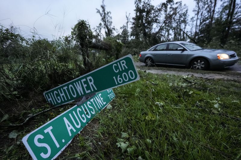 Vehicles move slowly around trees that have fallen after of Hurricane Helene moved through the area, Friday, Sept. 27, 2024, in Valdosta, Ga. (AP Photo/Mike Stewart)