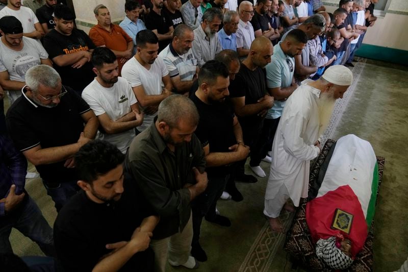 Palestinian mourners pray at the body of Mohammad Hoshiya, 12, during his funeral in the West Bank village of Qatana, southwest of Ramallah Saturday, June 22, 2024. Hoshiya succumbed to his wounds sustained during an Israeli army raid in the refugee camp of Amari last week, Palestinian ministry of health said. (AP Photo/Nasser Nasser)