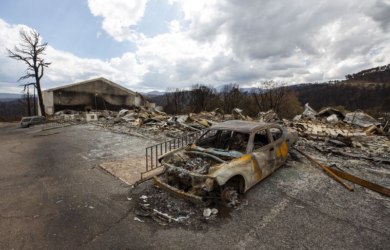 A charred car and the remains of the Swiss Chalet Hotel are shown after it was destroyed by the South Fork Fire in the mountain village of Ruidoso, N.M., Saturday, June 22, 2024. (AP Photo/Andres Leighton)