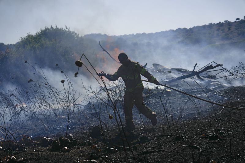 An Israeli firefighter works to extinguish a fire burning in an area near the community of Ramot Naftali, by the border with Lebanon, northern Israel, Tuesday, June 4, 2024. The Israeli military said Tuesday that six soldiers were lightly injured in a brush fire in the country's north that was sparked by fighting with the Lebanese militant group Hezbollah. (AP Photo/Ariel Schalit)