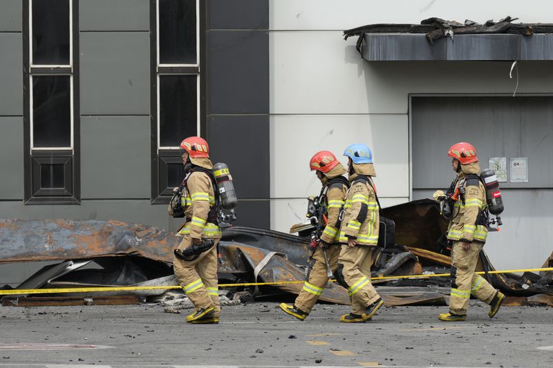 Firefighters walk near the debris at the site of a burnt battery manufacturing factory in Hwaseong, South Korea, Tuesday, June 25, 2024. (AP Photo/Lee Jin-man)
