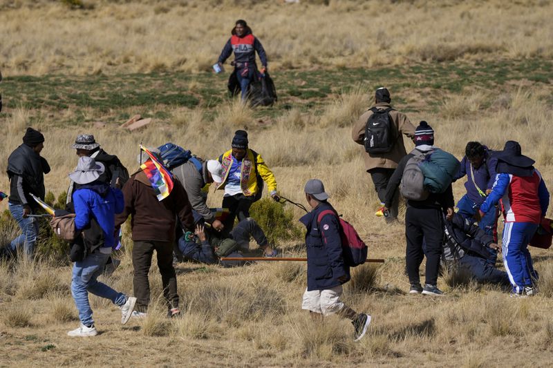 Supporters of former President Evo Morales kick a government supporter whose group confronted them in Vila Vila, Bolivia, during their march to the capital, Tuesday, Sept. 17, 2024. Morales and his supporters are marching to the capital to protest the government of President Luis Arce in an escalation of a political dispute between the two politicians. (AP Photo/Juan Karita)