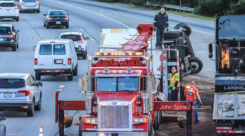 A wrecker clears an overturned tractor-trailer from the I-285 West ramp to Peachtree Industrial Boulevard. The truck tipped over about 6:15 a.m. Tuesday and blocked the ramp for several hours. JOHN SPINK / JSPINK@AJC.COM