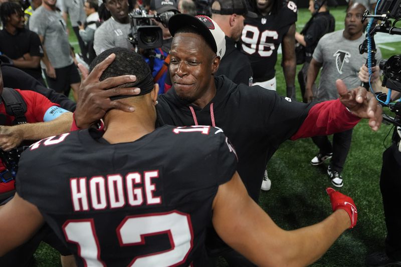 Atlanta Falcons head coach Raheem Morris celebrates with wide receiver KhaDarel Hodge (12) after scoring against the Tampa Bay Buccaneers during overtime in an NFL football game Thursday, Oct. 3, 2024, in Atlanta. (AP Photo/John Bazemore)