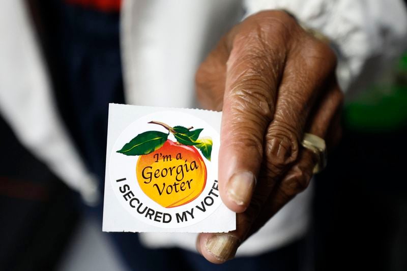 A poll worker holds a Georgia voter sticker ready to be handed to a voter at Berean Christian Church on Monday, Oct. 17, 2022. (Miguel Martinez/The Atlanta Journal-Constitution/TNS)