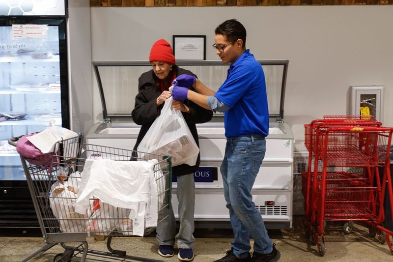 Valentin Chagolla, food pantry assistant manager at St. Vincent de Paul Society in Chamblee, assists Barbara Glasner with her groceries. Higher food prices are a special threat to metro Atlanta lower-income households that are already fighting to stay afloat. (Natrice Miller/ Natrice.miller@ajc.com)